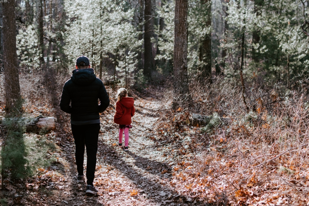Un enfant et un adulte qui se promènent dans une forêt pour évacuer le stress de noël